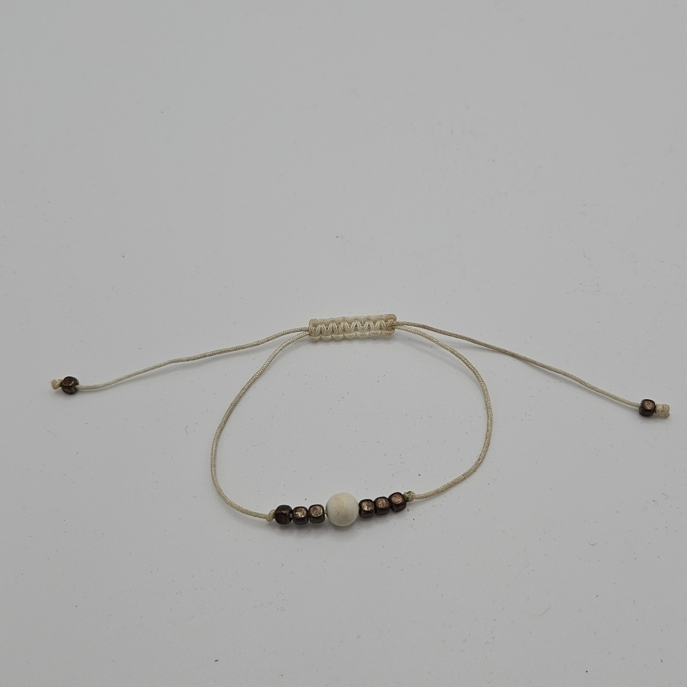 cream colored fabric slider bracelet with brass colored beads